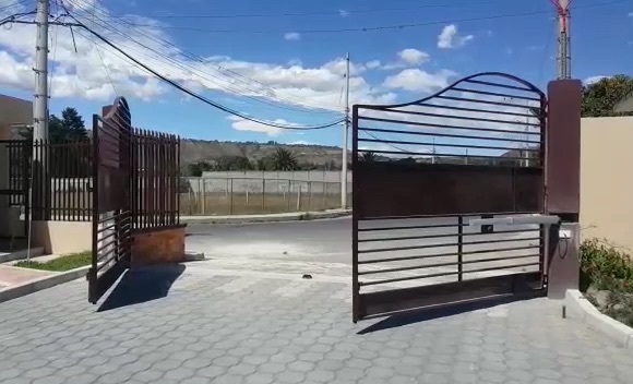 Port&oacute;n batiente met&aacute;lico abri&eacute;ndose con motor Erreka Vulcan en el ingreso de un conjunto