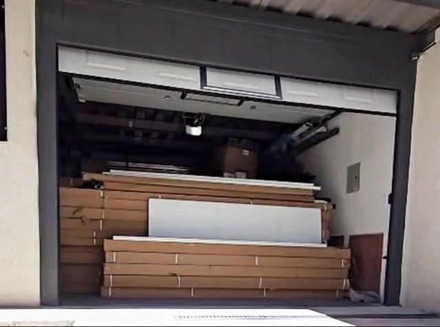 Puerta panelada blanca seccional abri&eacute;ndose en el ingreso de una bodega