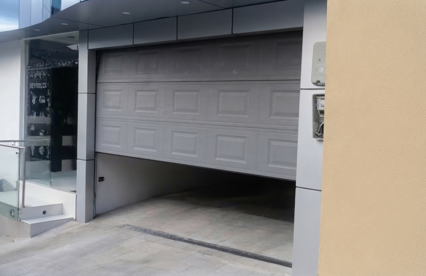 Puerta seccional gris instalada en el ingreso vehicular de un local comercial